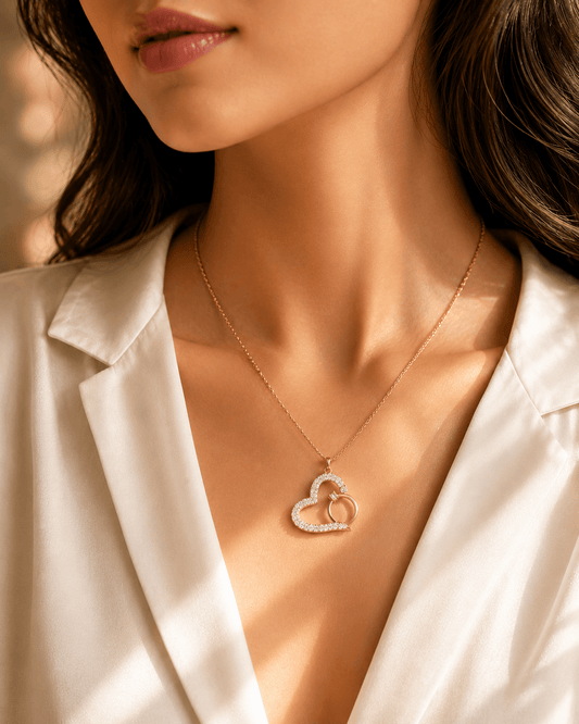 Gold-plated necklace features a pendant shaped like a heart with a smaller ring tucked inside