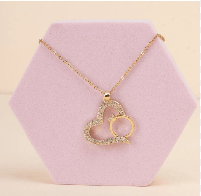Gold-plated necklace features a pendant shaped like a heart with a smaller ring tucked inside