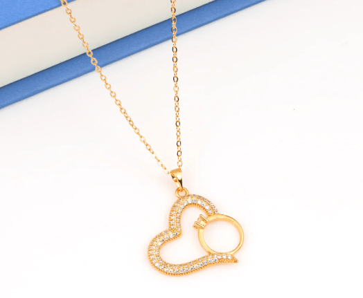Gold-plated necklace features a pendant shaped like a heart with a smaller ring tucked inside