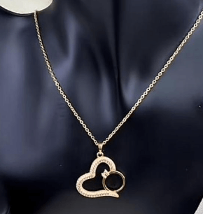 Gold-plated necklace features a pendant shaped like a heart with a smaller ring tucked inside
