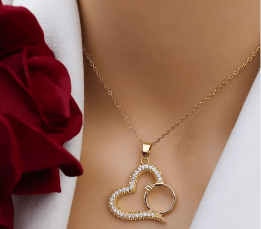 Gold-plated necklace features a pendant shaped like a heart with a smaller ring tucked inside